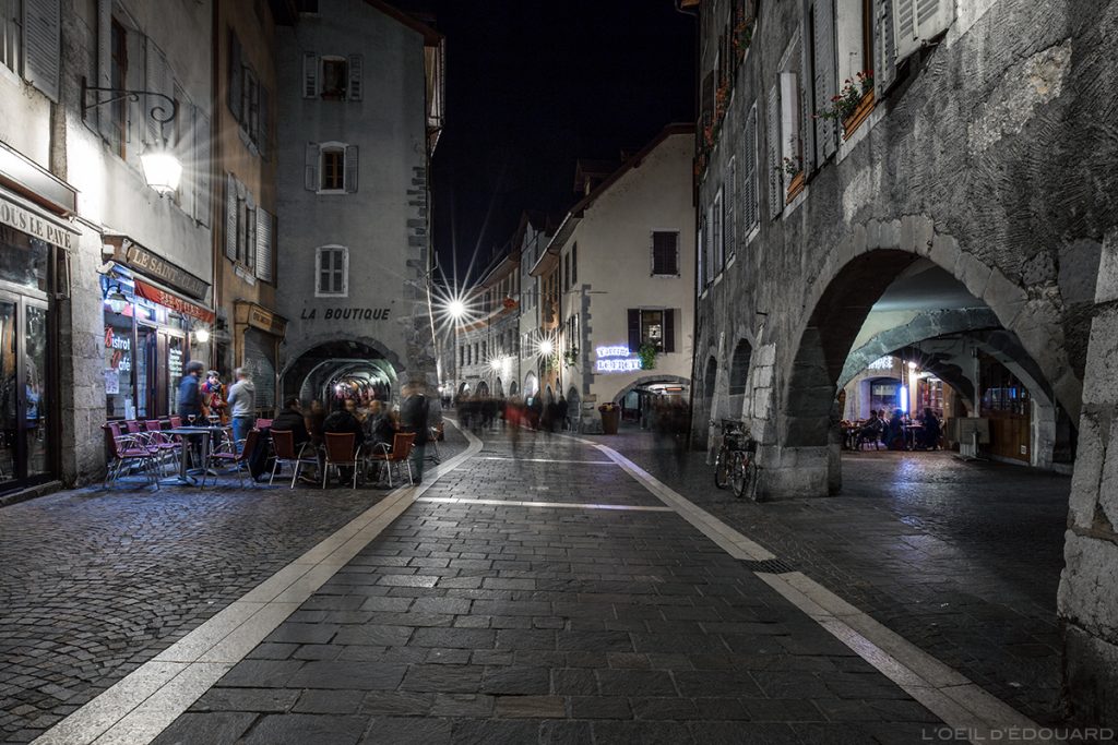 Rue Sainte-Claire la nuit dans la Vieille Ville d'Annecy avec les arcades et les terrasses © L'Oeil d'Édouard